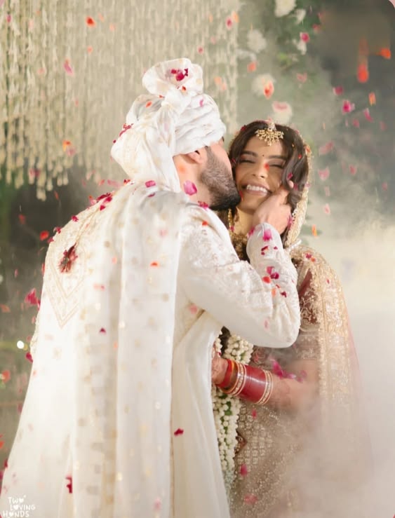 Groom kissing bride during rose petal shower